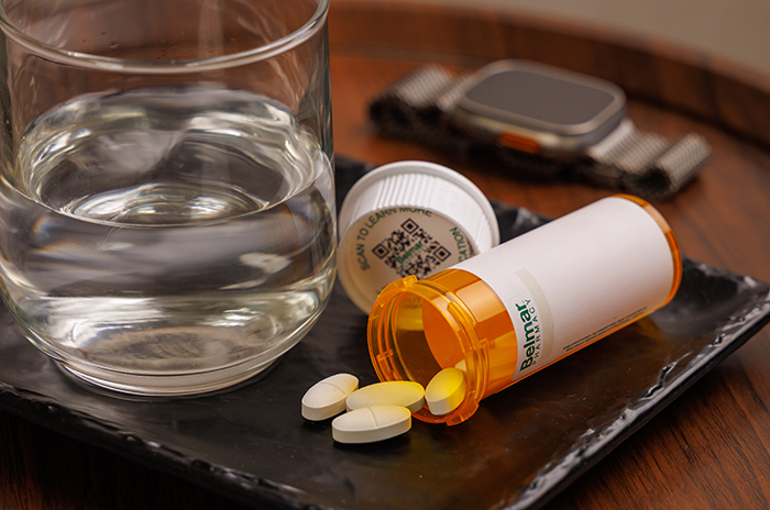 compounded medication bottle beside a glass of water
