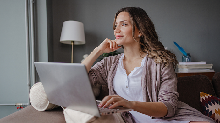 Woman with a laptop looking out the window.