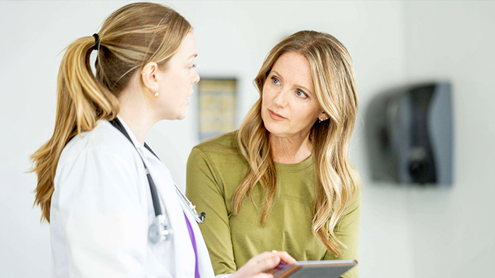 A doctor in a white coat talks to a patient during an appointment.
